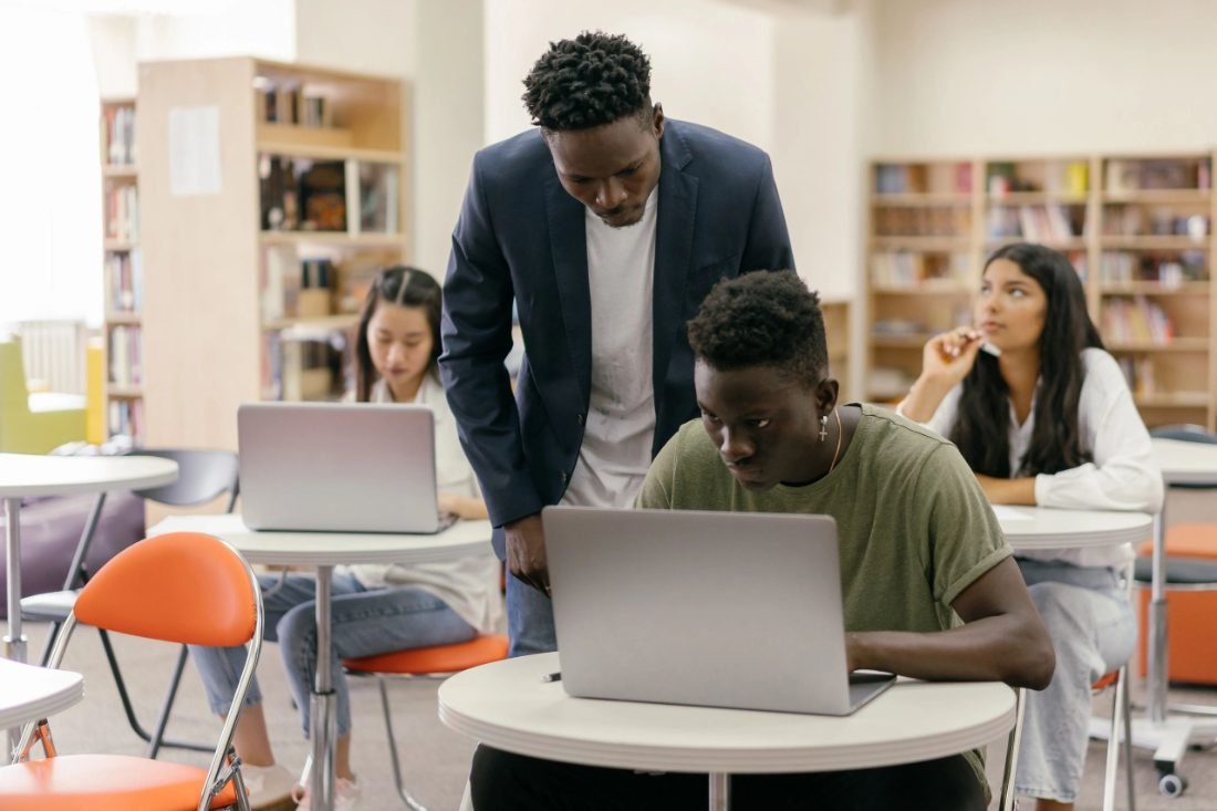 Students and a mentor working together at laptops in a library